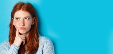 Sorunlu genç kızın kafasının görüntüsü, endişeli ve somurtkan bakışları, mavi arka plana karşı duruşu..