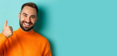 Çekici genç adamın yakın plan çekimi, iyi iş çıkarması, açık mavi arka planda durması, olumlu cevap vermesi..