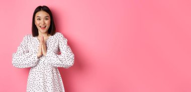 Güzel Asyalı kadın teşekkür ediyor. Takdir jesti olarak el ele tutuşuyor. Kameraya mutlu bir şekilde gülümsüyor..