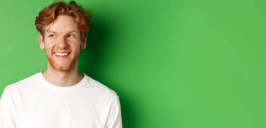 Sakallı, uzun kollu, beyaz saçlı, fotokopi odasına bakıp gülümseyen, yeşil arka planda duran mutlu kızıl adamın vesikalığı..