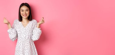 Koreli kalp işaretleri gösteren, gülümseyen, romantik pembe arka planda duran Asyalı güzel bir kadın..