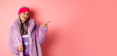 Memnun olmayan, şık, mor, sahte kürklü bir kadın. Parmağını sağa gösteriyor. Hoşnutsuzluktan suratını ekşitiyor..