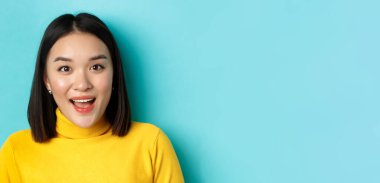 Güzellik ve cilt bakımı. Şaşırmış Asyalı kadın kaşlarını kaldırıyor ve kameraya eğlenceli bir şekilde bakıyor, ilginç bir şeye bakın, mavi arka planda duruyor..