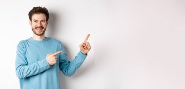 Mutlu sakallı adam reklamını yapıyor, parmaklarını doğru gösteriyor ve gülümsüyor, linke tıklamaya davet ediyor, beyaz arka planda duruyor..