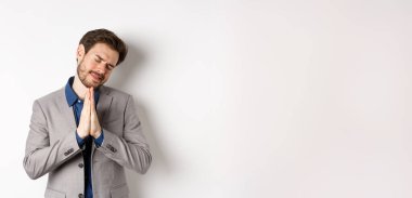 Yalvaran işadamı, el ele tutuşup dua ediyor ve yardım istiyor. Bir şeye ihtiyacın var, lütfen söyle, beyaz arka planda duruyor..