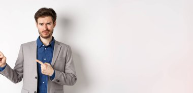 Kötü bir fikir. Memnun olmayan şüpheci takım elbiseli adam sırıtıyor ve kaşlarını çatıyor. Üzücü haberleri işaret ediyor. Kameraya tereddütlü bakıyor..