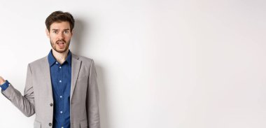 Yanlış olan ne? Takım elbiseli kafası karışık adam anlayamaz. Elleri havada, kameraya bakıyor, sorgulanıyor, beyaz arka planda duruyor..