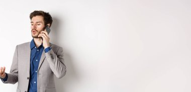 Yakışıklı işadamının telefonda iş görüşmesi cep telefonuyla konuşurken el kol hareketi yapması, sohbet etmesi, beyaz arka plan..