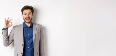 Heyecanlı sakallı iş adamı hayran hayran hayran hayran hayran hayran hayran hayran bakıyor ve evet diyor, onaylıyor ve iyi bir ürün gibi beyaz arka planda duruyor..