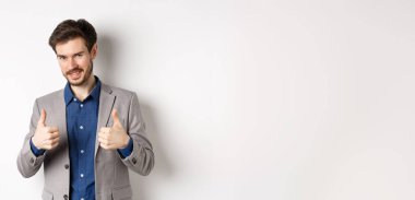 - Çok iyi. Gülümseyen yakışıklı yönetici onaylanmış, gururlu ve memnun görünüyor, evet diyor, iyi iş çıkarıyor, beyaz arka planda duruyor..