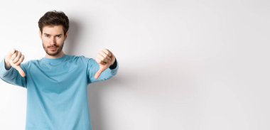 Şüpheli, sakallı yakışıklı, onaylamayan, kötü bir şeyden hoşlanmayan, beyaz arka planda duran..