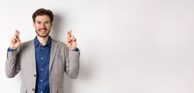 Umut dolu gülümseyen işadamı iyimser görünüyor, şans diliyor, kazanmak için dua ediyor, umutla sonuçları bekliyor, beyaz arka planda duruyor..