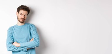 Kararsız ve düşünceli sakallı bir adam düşünceli, dalgın dalgın bakıyor ve seçim yapıyor, beyaz arka planda duruyor..