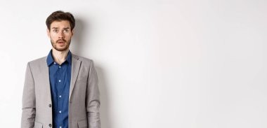 Takım elbiseli şaşkın sakallı işadamı sağ üst köşedeki logoya bakıyor..