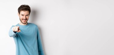 Kendine güvenen, gülümseyen, kamerayı işaret eden, seni davet eden ve seçen genç bir adam görüntüsü..