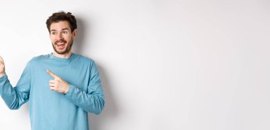 Heyecanlı sakallı adam özel teklifi kontrol ediyor, mutlu yüzle reklamlara bakıyor, beyaz arka planda duruyor..