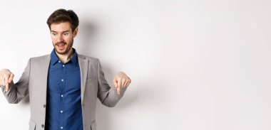 Heyecanlı takım elbiseli, gülümseyen ve parmakla işaret eden, gülen yüzlü, beyaz arka planda duran, özel muamele gören adam..