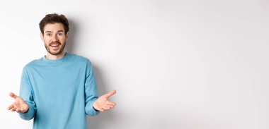 Yakışıklı genç adam senin için mutlu hissediyor, kameraya el kaldırıyor ve iyi işi övüyor, tebrik ediyor, beyaz arka planda duruyor..