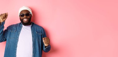 Bereli mutlu bir siyah adam. Neşeli bir güneş gözlüğü. Mutlu bir yüzle dans ediyor..