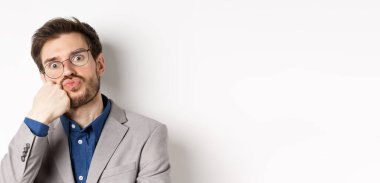 Gözlüklü komik ofis çalışanı, somurtuyor, nefes alıyor, kameraya bakıyor, beyaz arka plan.