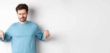 Şüpheci çocuk, beyaz arka planda duran, kötü tanıtım teklifine bakan, ve hayal kırıklığına uğramış,.