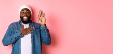 Gülümseyen Afro-Amerikan bir adamın dürüst olması, doğruyu söylemesi, ellerini havaya kaldırması, söz vermesi ya da küfretmesi, pembe arka planda durması..