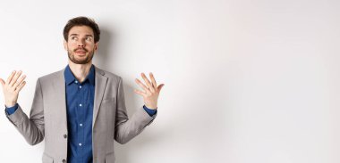 Takım elbiseli genç yöneticinin biraz havaya ihtiyacı var. Kızarık ve sinirli hissederek el sallıyor. Beyaz arka planda duruyor..