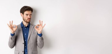 - Çok iyi. Takım elbiseli yakışıklı adam göz kırpıyor ve tamam işareti gösteriyor. Kıyafetini beğeniyor ve onaylıyor. Seçimini övüyor..