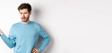 Ne olmuş yani? Kafası karışmış genç adam elini kaldırıyor ve kameraya şüpheci bakıyor, hiçbir şey bilmiyor, bir şey anlayamıyor, beyaz arka planda duruyor..