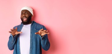 Tiksindirici, seçici siyah adam imajı rahatsız edici, kötü teklifi reddeden, nefret ve nefretle yüzünü buruşturan, pembe arka planda duran.