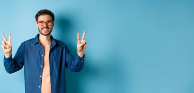 Yeni gözlüklü, barış simgesiyle poz veren neşeli bir adam..