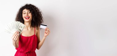 Alışverişe. Kıvırcık saçlı, kırmızı elbiseli, elinde plastik kredi kartıyla zengin ve başarılı bir kadın..