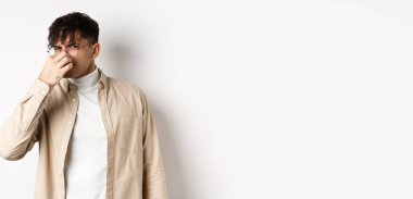 İğrenç kokudan burnunu kapatmış iğrenç ve pis kokulu bir şeye bakıp beyaz arka planda duran iğrenç bir adamın görüntüsü..