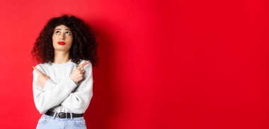 Kırmızı dudaklı, kıvırcık saçlı, seçimle ilgili sorunları araştıran, yan tarafları işaret eden, iki ürün arasında seçim yapan,.