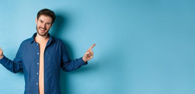 Sakallı, beyaz dişleriyle gülümseyen, iki seçeneği gösteren, mavi arka planda duran, beyaz saçlı yakışıklı beyaz adam..