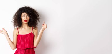 Annoyed caucasian woman in red dress, showing finger without wedding ring, arguing about marriage, standing pissed-off on white background.