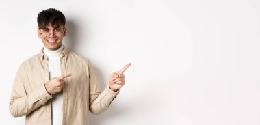 Gözlüklü yakışıklı beyaz adam gülümsüyor, sağ üst köşeyi işaret ediyor, beyaz arka planda logo gösteriyor..