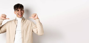 Motive olmuş, gülümseyen, kendini gösteren, kendine güvenen, beyaz arka planda duran yakışıklı bir adam..