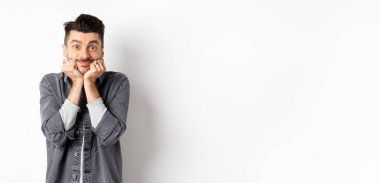 Bıyıklı, tatlı bir genç adam gülümseyen ve kameraya rüya gibi bakan, güzel bir şeye bakan, gerçek güzelliğe hayran olan, beyaz arka planda duran..