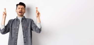 Üzgün ve sefil bir adam, Tanrı 'yı umuyor, dua ediyor, dua ediyor ya da umutsuz bir suratla dilek tutuyor, beyaz arka planda duruyor..