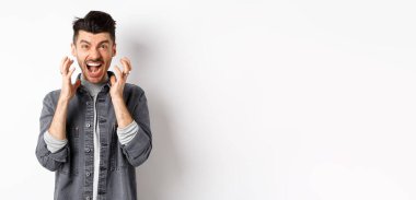 Öfkeli adam bağırıyor, sinirden kuduruyor ve sinirden köpürüyor, kötü bir şeye bakıyor, beyaz arka planda duruyor..