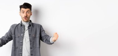 Büyük boyutlarda, büyük nesneleri şekillendiren, beyaz arka planda duran heyecanlı beyaz adam..