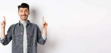 Bıyıklı neşeli beyaz adam yukarı bakıyor, gülümsüyor, hayal kuruyor, havalı bir terfi anlaşması yapıyor, beyaz arka planda duruyor..