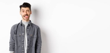 Bıyıklı komik adam dil gösteriyor ve göz kırpıyor, seni güldürüyor, beyaz arka planda duruyor..