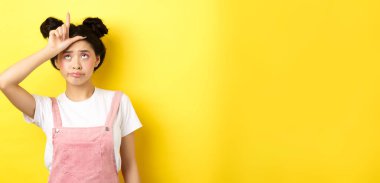 Alnında ezik işareti olan üzgün kız üzgün, kendini hayal kırıklığına uğramış hissediyor, sarı arka planda duruyor..