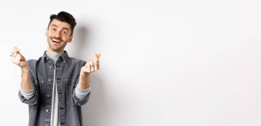 Yakışıklı, gülümseyen bir adam. Kalplerini gösteriyor ve kameraya aşkla bakıyor. Beyaz arka planda duruyor..