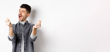 Komik adam göz kırpıyor, el işareti yapıyor, romantik ve mutlu hissediyor, beyaz arka planda duruyor..