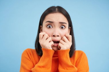 Koreli korkmuş kadının çığlıklarına yakından bakın, dehşete düşmüş görünüyor, mavi arka planda duruyor. Boşluğu kopyala