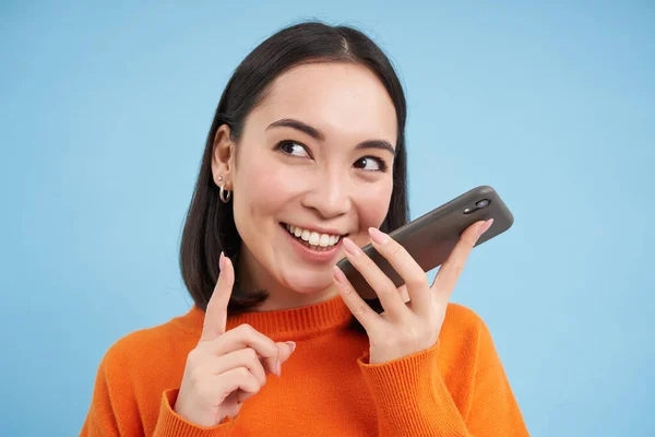 韩国女性的肖像在智能手机应用中记录语音信息 在扬声器上交谈 在移动应用中翻译她的演讲 蓝色背景 — 图库照片