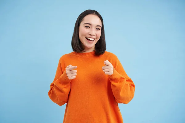 You got this, good job. Enthusiastic korean woman, points at camera with finger pistols and smiles, encourages, praises, stands over blue background.